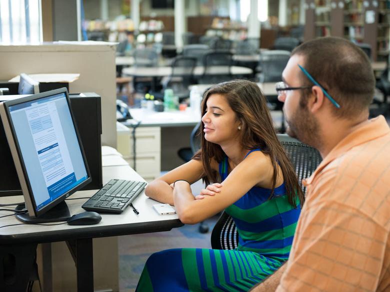 Female student working with male adviser on computer